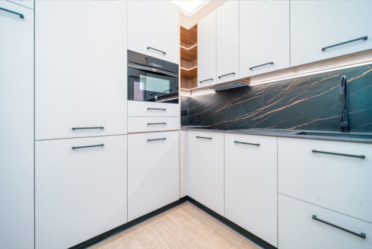 Cocina blanca a medida con encimera oscura veteada e iluminación integrada
